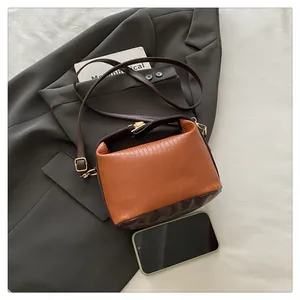 Detail of color-block handbag with pleated texture and smartphone for size reference