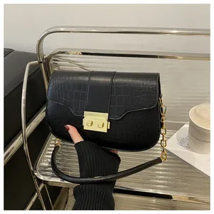 Close-up of black crocodile embossed shoulder bag featuring a gold clasp and chain strap