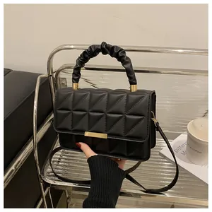 Close-up of black quilted crossbody bag with a ruched top handle and golden hardware