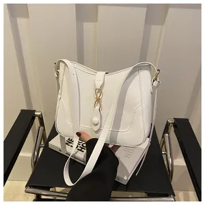 Detail view of white crescent bag with gold metal buckle and fine stitching on leather seat