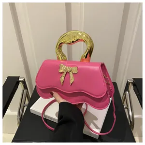 Detail of rose pink handbag featuring unique wavy flap and golden bow ornament