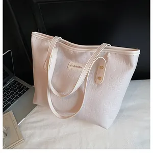Detail of cream tote bag with embossed geometric patterns and fashion leather tag