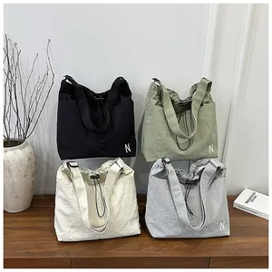 Detailed display of drawstring nylon tote bags in four colors on a wooden surface