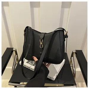Close-up of minimalist black matte leather shoulder bag with decorative gold metal buckle
