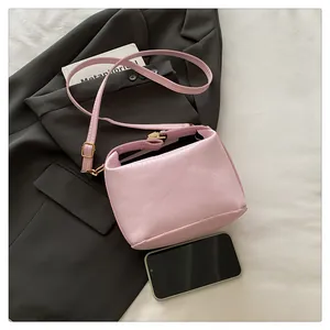 Close-up of pink pleated leather crossbody bag with light gold metal hardware details