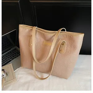 Detail of beige tote bag with embossed letter patterns and golden FASHION metal logo