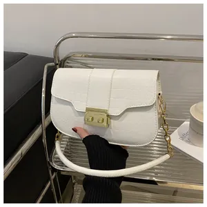 Detail of white croc-embossed texture and golden square metal lock on the stylish handbag