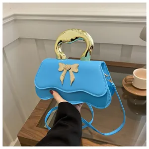 Close-up of sky blue wavy handbag featuring a gold heart bow buckle and metal handle