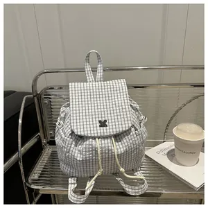 Detail of the blue and white checkered backpack featuring drawstring and metal clasp