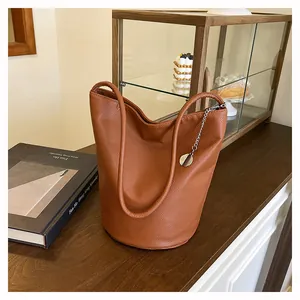 Close-up of caramel brown leather bucket bag with lychee texture and silver chain detail