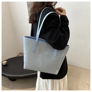 Detail of light blue tote bag with unique crinkled texture and golden rivet accents