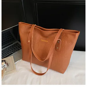 Close-up of brown PU tote bag with letter embossing and metal rivet reinforcements