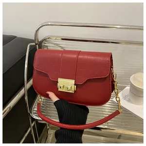 Detail of red crocodile pattern handbag featuring a gold rectangle lock and chain strap
