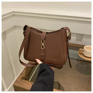 Close-up of retro dark brown leather underarm bag featuring a golden figure-8 metal buckle