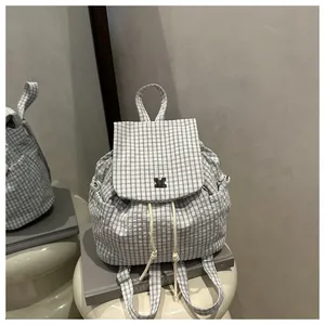 Detail of checkered drawstring backpack with flap closure and side pockets on a stool