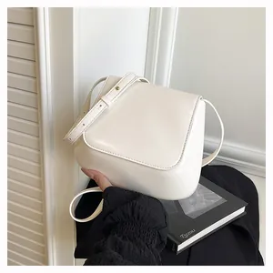 Detail view of cream minimalist shoulder bag with smooth leather texture and gold buckle