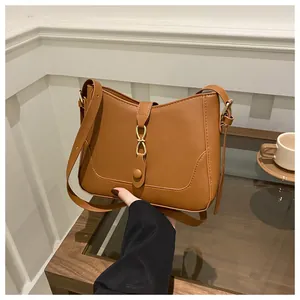 Detailed close-up of brown faux leather shoulder bag with decorative metal twist lock