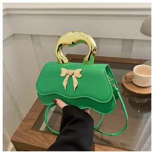 Detailed view of green bow handbag with a wavy flap and golden semicircular handle