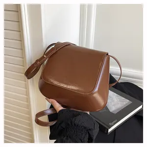 Close-up of a brown leather shoulder bag featuring a smooth matte finish and flap closure