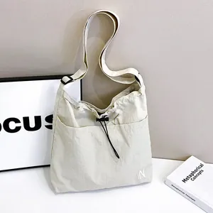 Minimalist cream drawstring crossbody bag with N embroidery and adjustable strap