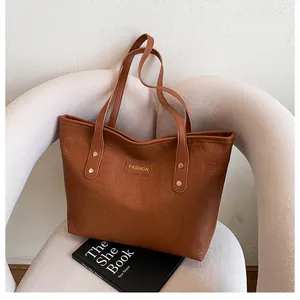Detail of a brown embossed tote bag with gold lettering on a white designer chair
