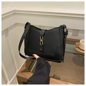 Close-up of black leather underarm bag with gold double-ring buckle and fine stitching