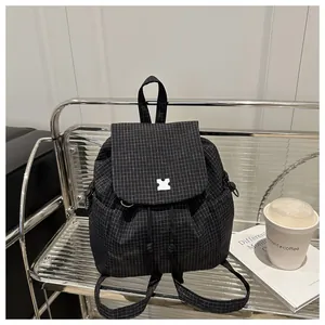 Detailed view of checkered canvas backpack with drawstring closure and decorative buckle