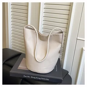 Detail of minimalist beige leather bucket bag with litchi texture on a black book