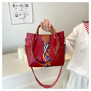 Dettaglio della borsa tote rossa con nastro etnico geometrico e manici in pelle marrone