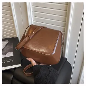 Detailed close-up of brown faux leather shoulder bag with gold buckle and fine stitching