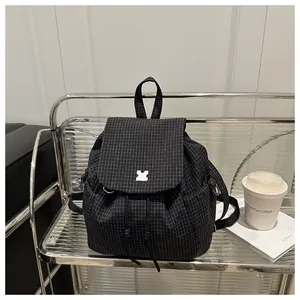 Detail of black checkered drawstring backpack on metal shelf with modern urban accessories