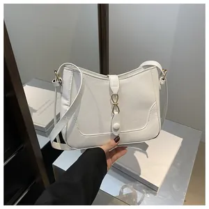 Detail of white PU leather shoulder bag with gold metal infinity buckle and strap