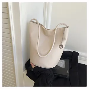 Detailed macro of cream bucket bag showing lychee grain leather and silver chain strap
