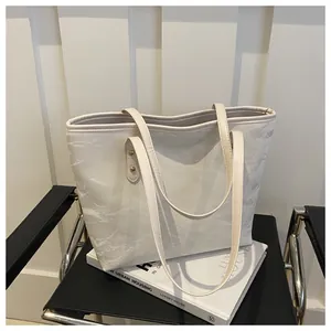 Close-up of white marble texture tote bag with golden rivets on a black chair