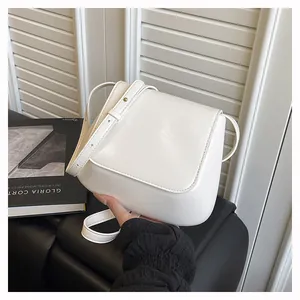Detail view of the white flap shoulder bag with adjustable leather strap and metal hardware