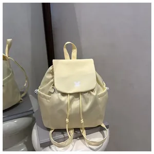 Detail of light yellow drawstring backpack with white logo on a lifestyle background