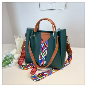 Dettaglio della borsa in pelle verde scuro con tracolla intrecciata geometrica colorata