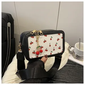 Detail of cherry print crossbody bag featuring metal zippers and a 3D cherry charm