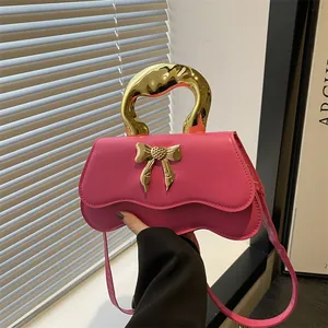 Hot pink crossbody bag with melting gold handle and bow detail on wavy base design
