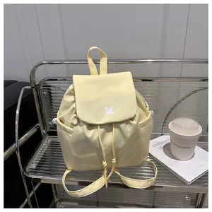 Detail of pale yellow drawstring backpack with flap closure on silver mesh shelf
