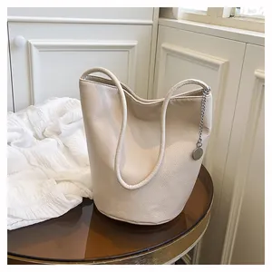 Detail of soft off-white bucket bag with lychee grain leather texture and metal tag