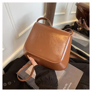 Detailed view of caramel brown glossy PU leather texture and flap design on crossbody bag