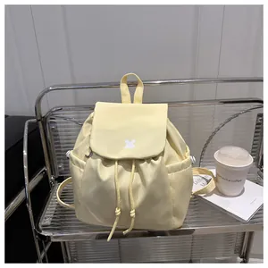 Detail of light yellow drawstring backpack with front logo and side storage pocket