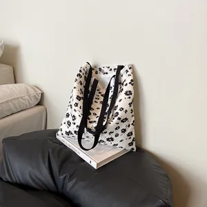Floral canvas tote bag with white lace trim and black shoulder strap on art book