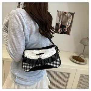 Detail of checkered underarm bag with black bow and silver heart pendant on strap