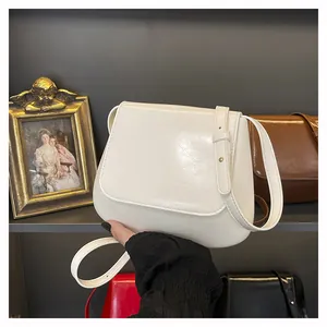 Close-up of a cream white leather shoulder bag displayed in a vintage gold frame