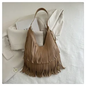 Detail einer braunen Leder-Schultertasche mit langen Fransen über Anzug und Buch