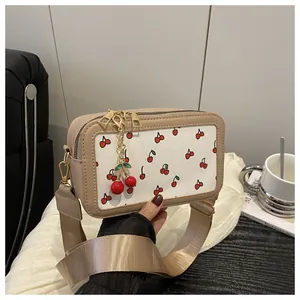 Close-up of cherry print square bag with red cherry charm and golden dual zippers