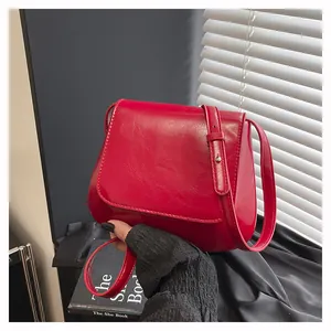 Close-up of vibrant red leather shoulder bag with glossy texture and adjustable strap