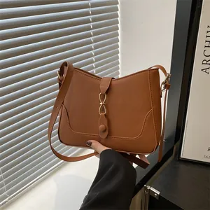Chic caramel brown underarm shoulder bag with gold buckle and stylish u-shaped stitching
